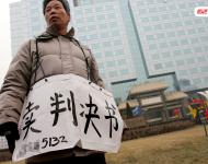 2006年1月24日，在京從事降水井工程的老陳掛著寫有“賣判決書”的紙口袋在北京站口附近來回走著。曾是名小工頭的老陳被欠工程款4萬元，為了給工人們開資不得已賣掉了打井機(jī)器。2002年法院宣判老陳勝訴，可四年后該判決仍得不到執(zhí)行，無奈之中老陳只好上演此幕。程寧/視覺中國
